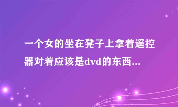 一个女的坐在凳子上拿着遥控器对着应该是dvd的东西按了一下，然后就捂着下面开始不停的抖